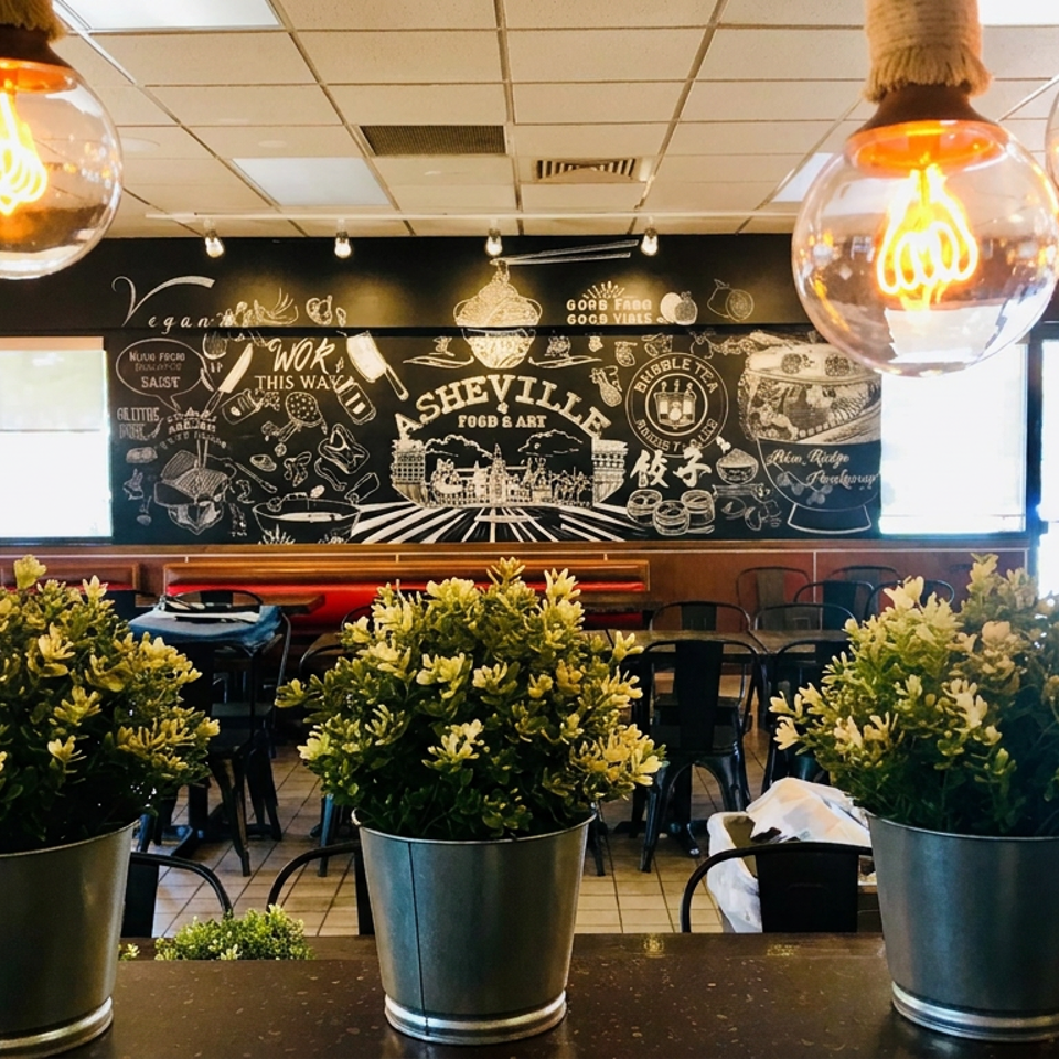 Bright Asheville restaurant interior with potted plants, red booths, pendant lights, and a large illustrated food-themed mural.